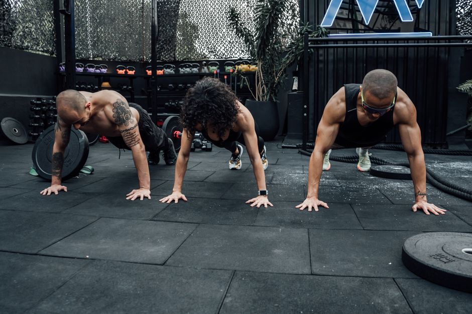 Three individuals performing push-ups together in a Mexico City gym setting