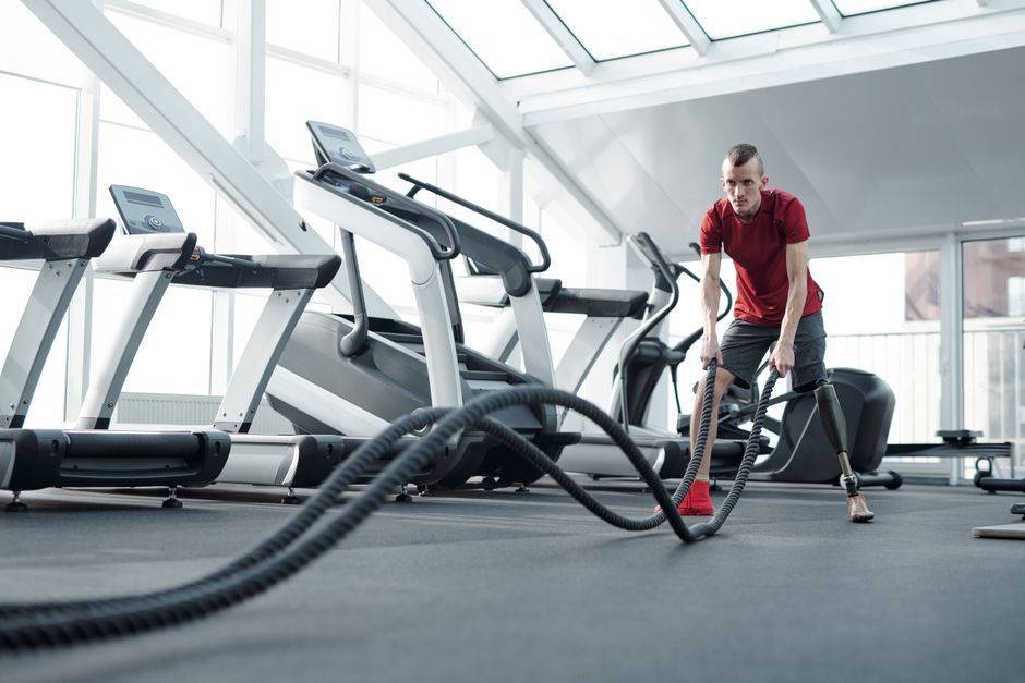 Young man with prosthetic leg working out with battle ropes