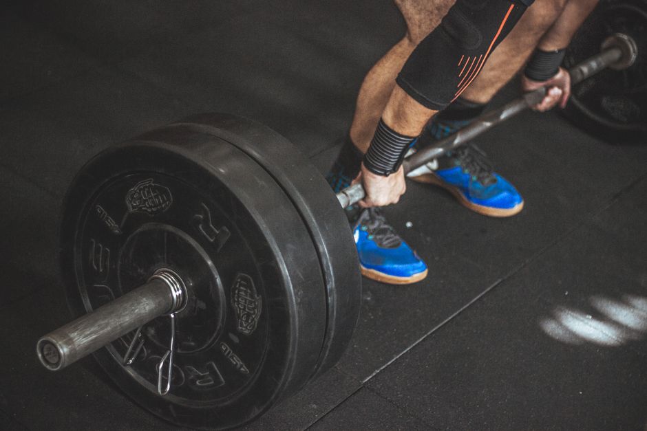 A man performing a deadlift with a heavy barbell in a gym setting