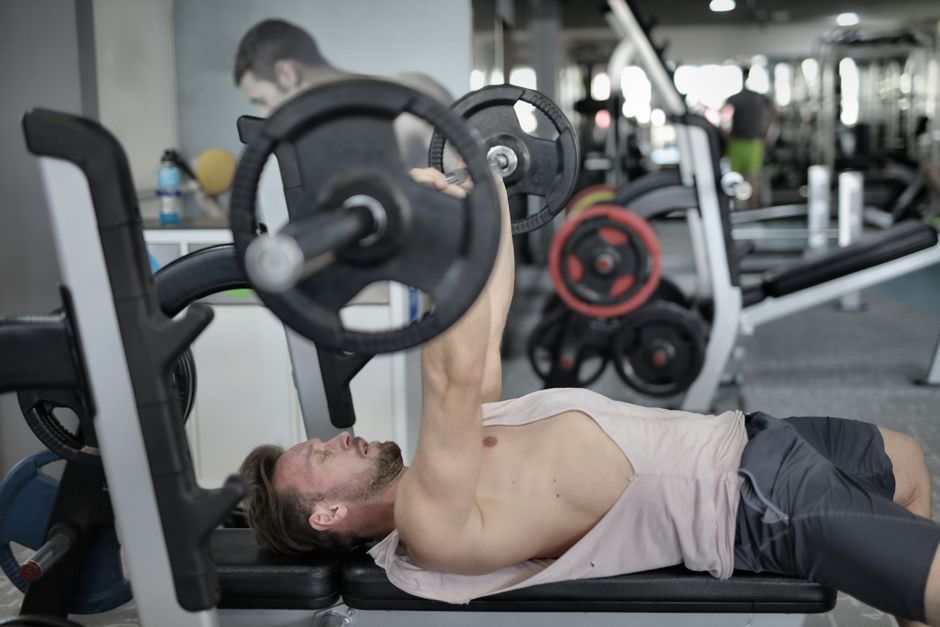 Strong young sportsman lying on bench pressing heavy barbell