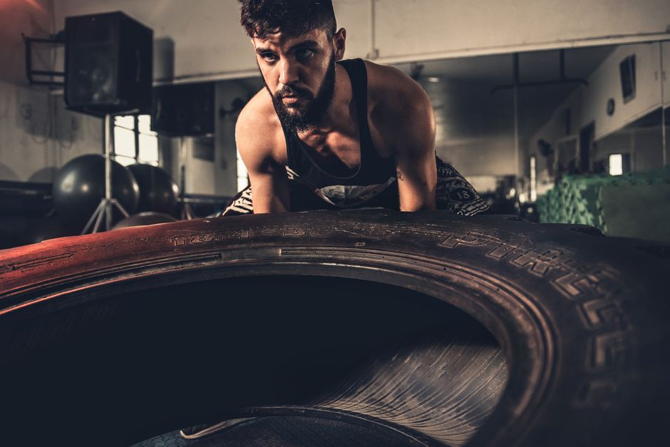 Man focusing intensely while flipping a large tire during a crossfit workout