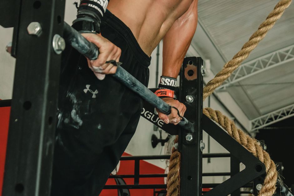 A muscular man performing a pull-up exercise indoors, showcasing strength and fitness